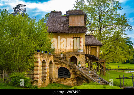 Lovely side view of the Mill with its garden, a rustic building with a thatched rooftop in the Queen's Hamlet surrounded by trees in the park of the... Stock Photo