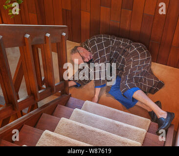 A senior man trying to get up after falling down the stairs Stock Photo
