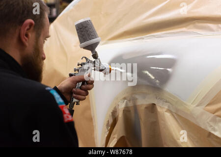 “Bonhomme Automobile” car body shop in Montelier (southeastern France). Worker spraying paint on a car body. Stock Photo