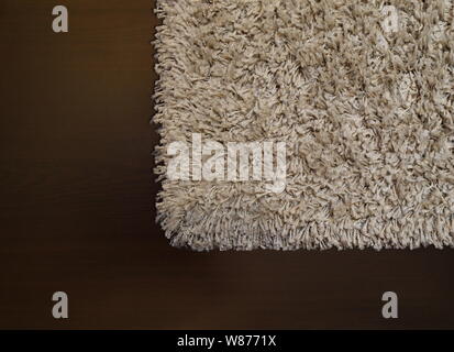 Beige shaggy carpet on wenge floor Stock Photo
