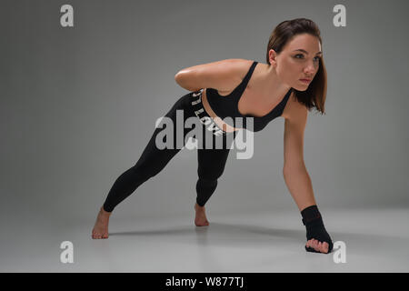 Athletic woman in boxing mittens is practicing karate in studio. Stock Photo