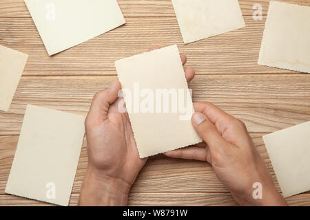 Old photo in the hands of man. Empty template for picture, mock-up. Wooden background Stock Photo