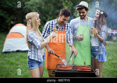 Happy group of friends making a barbecue together outdoors in the nature Stock Photo