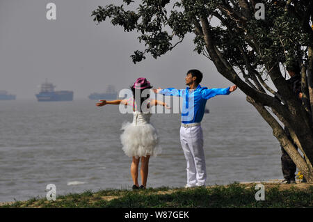 A young Chinese couple have their wedding photographs taken on the bank of the Yangtse river Nantong China Stock Photo