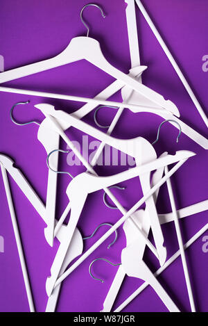 White clothes hangers on violet background with copy space. Flat lay. Top view. Minimalism style. Creative layout. Fashion, store sale, shopping conce Stock Photo