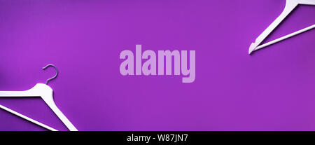 White clothes hangers on violet background with copy space. Flat lay. Top view. Minimalism style. Creative layout. Fashion, store sale, shopping conce Stock Photo