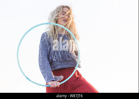 Girl performs hooping, captured in mid air, looking through hoop against a white background.  Cutout. Stock Photo