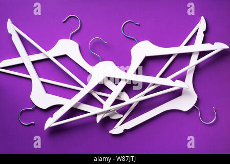 White clothes hangers on violet background with copy space. Flat lay. Top view. Minimalism style. Creative layout. Fashion, store sale, shopping conce Stock Photo