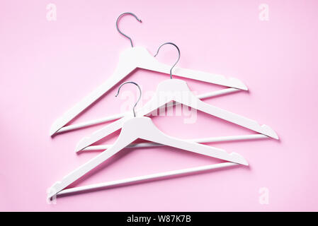 White clothes hangers on pink background with copy space. Flat lay. Top view. Minimalism style. Creative layout. Fashion, store sale, shopping concept Stock Photo