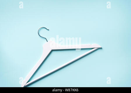 White clothes hangers on blue background with copy space. Flat lay. Top view. Minimalism style. Creative layout. Fashion, store sale, shopping concept Stock Photo