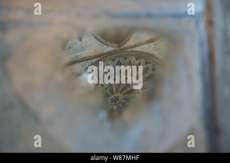 York Minster's Rose Window reflected in puddle in flagstone pavement Stock Photo