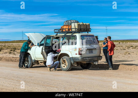 Car accident : Driver and Tourists fix broken car during 4x4 Jeep Tour on Bolivian Altiplano close to salt flats of Salar de Uyuni Stock Photo
