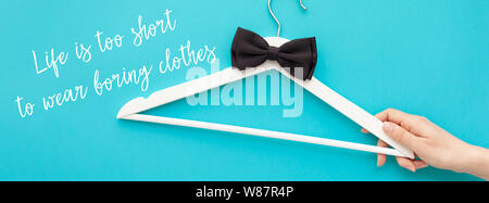 Creative top view flat lay white wooden hangers with hand bold turquoise background with text message Life is too short to wear boring clothes. Templa Stock Photo