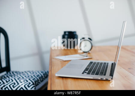 Comfortable working place in home office with wooden table and modern laptop on it. Freelance work concept Stock Photo