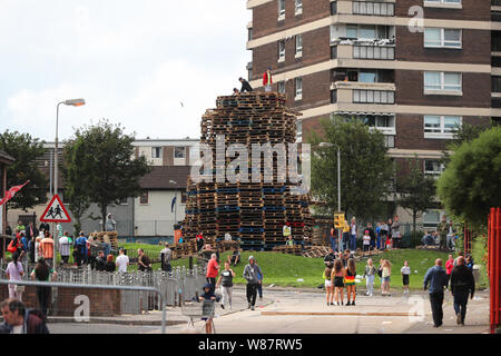 People standing on top of a bonfire in north Belfast, which contractors have been ordered to remove. A stand-off has developed between police and those supporting the bonfire, and a number of missiles have been thrown at officers. Stock Photo