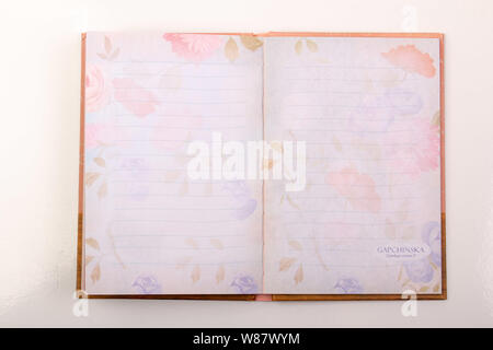An open notebook on the table on a white background. Diary with pink pages. Planners Stock Photo