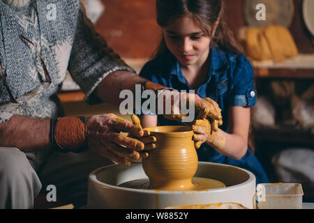 Pottery workshop. Grandpa teaches granddaughter pottery. Clay modeling Stock Photo