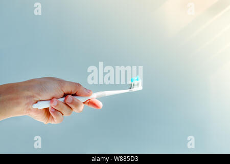 Woman hand holding toothbrush with toothpaste applied on. Closeup of  white toothbrush with blue tooth paste Stock Photo