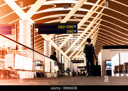 SHANGHAI, CHINA - FEB 2019: traveler with travel bag or luggage walking in the airport terminal walkway for air traveling Stock Photo