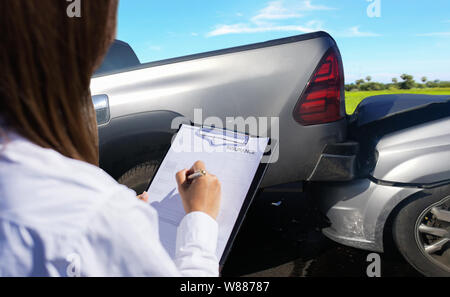 Insurance agent examines damaged car and customer filing signature on report claim form process after accident, Traffic Accident and insurance concept Stock Photo