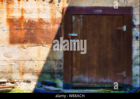 Close up of an exterior wall of an old mill with a locked storage door. Stock Photo