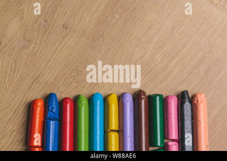 Colourful used crayons in a row on a wooden surface