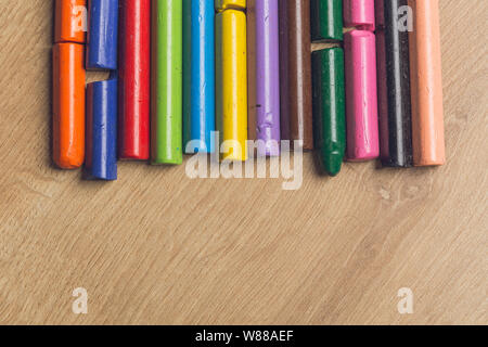 Colourful used crayons in a row on a wooden surface