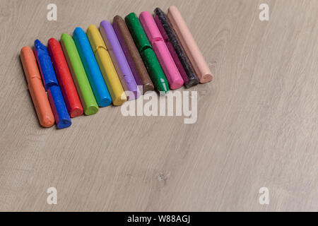 Colourful used crayons in a row on a wooden surface Stock Photo