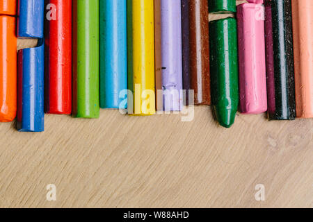Colourful used crayons in a row on a wooden surface
