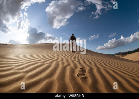 One lonely man walks in desert on dunes Stock Photo