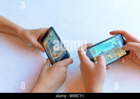 Bishkek, Kyrgyzstan - January 17, 2019: Two friends play pubg coop multiplayer battle royale game on iPhone and Android. Gameplay action Stock Photo