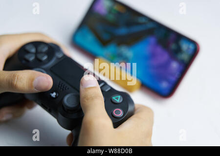 Bishkek, Kyrgyzstan - June 06, 2019: Man playing games on Apple arcade subscription system on ios 13 with sony dualshock gamepad Stock Photo