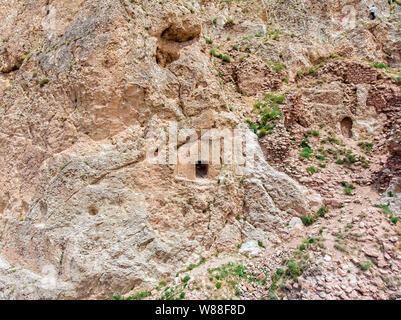 Aerial view of bas-reliefs carved in the rock that adorn the entrance frame of a house carved into the rock on the steep side of a mountain. Turkey Stock Photo