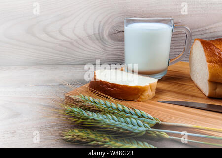 Wheat ears of milk white bread on a wooden background Stock Photo