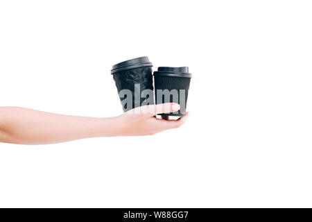 Two black paper coffee cups to go in woman's hand isolated on white. Mockup. Stock Photo
