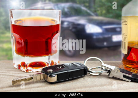 Subject drunk videl behind the wheel. Car keys with a glass of liquor on the background of the car. Stock Photo
