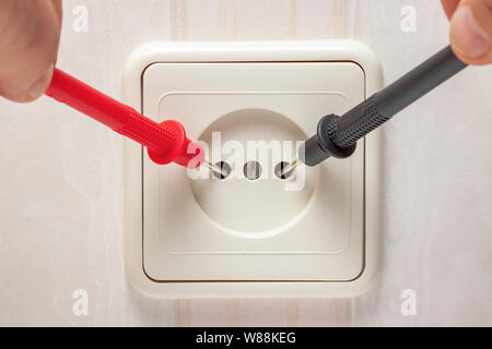 Measurement of electricity in the outlet using a multimeter in hand. High-quality close-up photography. Stock Photo