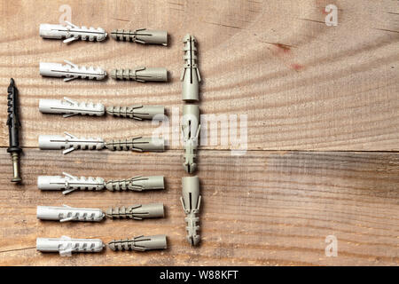 Plastic dowels lie in a row on a wooden background Stock Photo