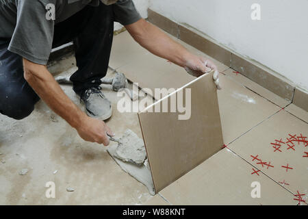 Gluing tiles on the wall. Laying tiles on the wall.  Worker installing big ceramic tiles on the walls Stock Photo