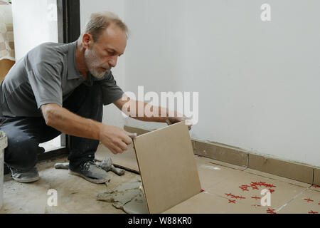 Gluing tiles on the floor. Laying tiles on the floor.  Worker installing ceramic tiles on the floor Stock Photo
