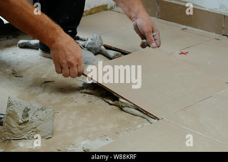 Gluing tiles on the floor. Laying tiles on the floor.  Worker installing ceramic tiles on the floor Stock Photo