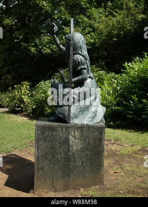 Bronze sculpture of Alice looking through the looking glass by Jean Argent in the grounds of Guildford Castle, Surrey Stock Photo