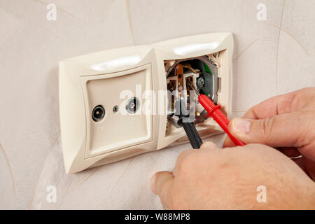 Measurement of electricity in the outlet using a multimeter in hand. High-quality close-up photography. Stock Photo