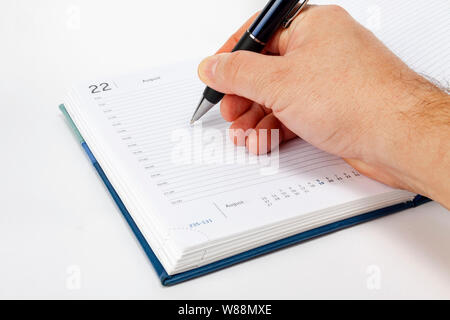 Hand writes with a pen in the weekly Stock Photo