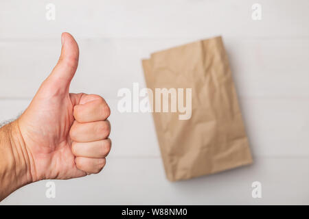 Close up male hand with thumb up over brown empty crumpled craft paper bag. Zero waste, plastic free concept Stock Photo