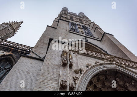 89-meter-tall Gothic tower of Saint Bavo Cathedral (Sint-Baafs Cathedral) shot from low angle. It is the oldest parish church in Ghent Stock Photo