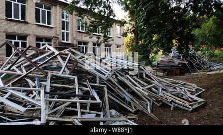 Photo with large pile of old wooden windows that were replaced with plastic windows against the background of a building under repair, selective focus Stock Photo