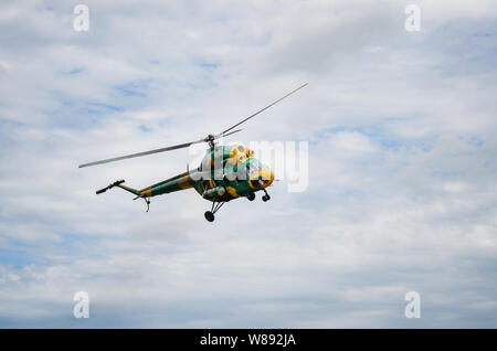 Khaki colored helicopter is flying in blue sky Stock Photo