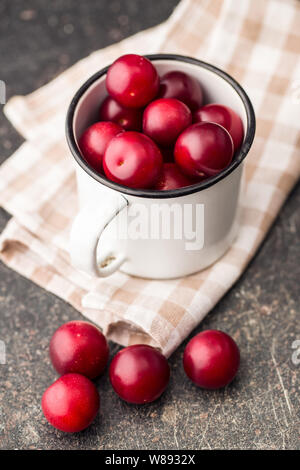 The red cherry plums fruit in mug. Stock Photo