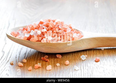 Wooden spoon with large crystals of pink himalayan salt over wooden background. Himalayan salt is used in cooking, medicine and cosmetology. Stock Photo